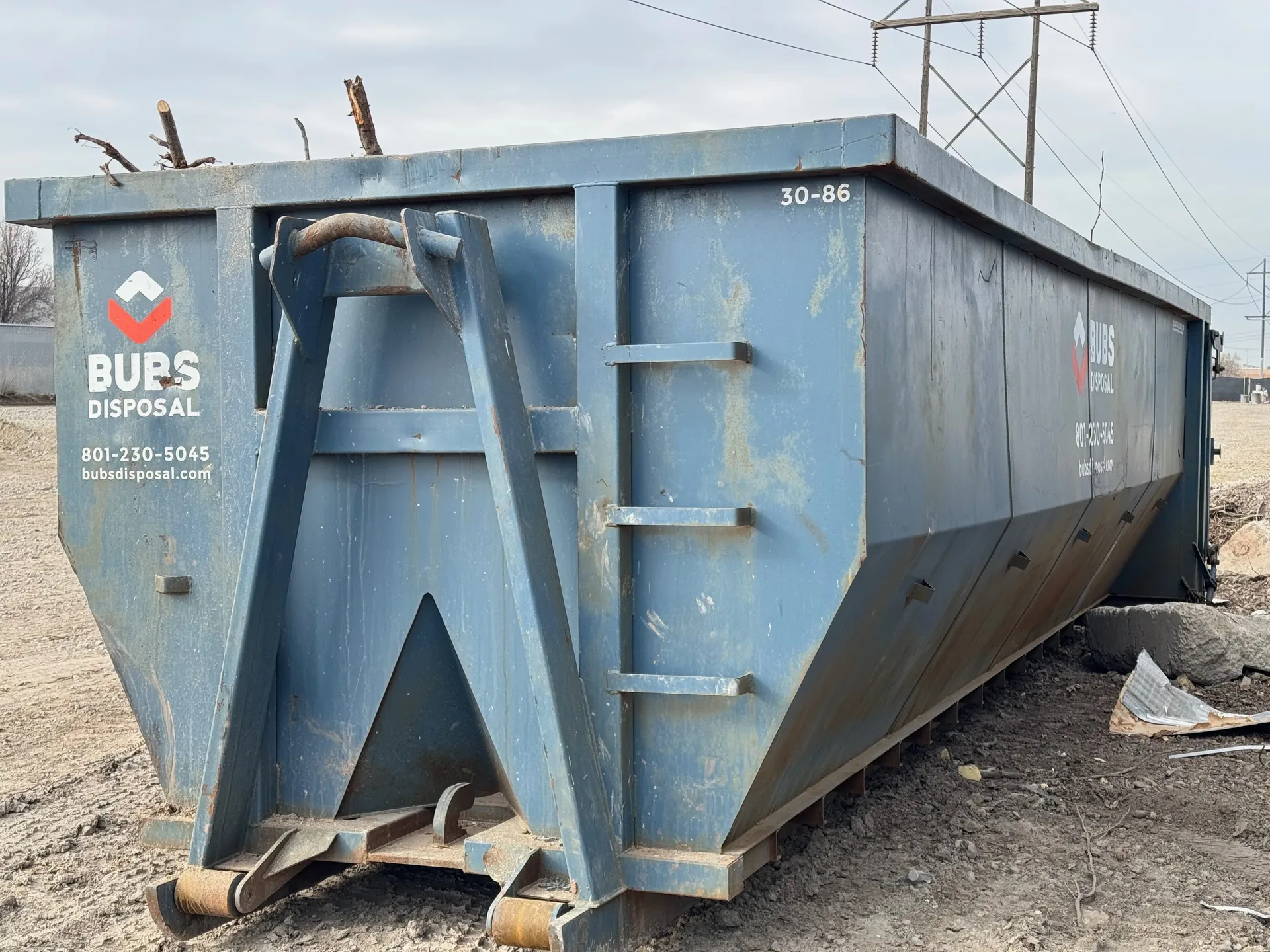 Bubs Disposal 30 yard dumpster on a job at an industrial site near power lines with Wasatch mountains