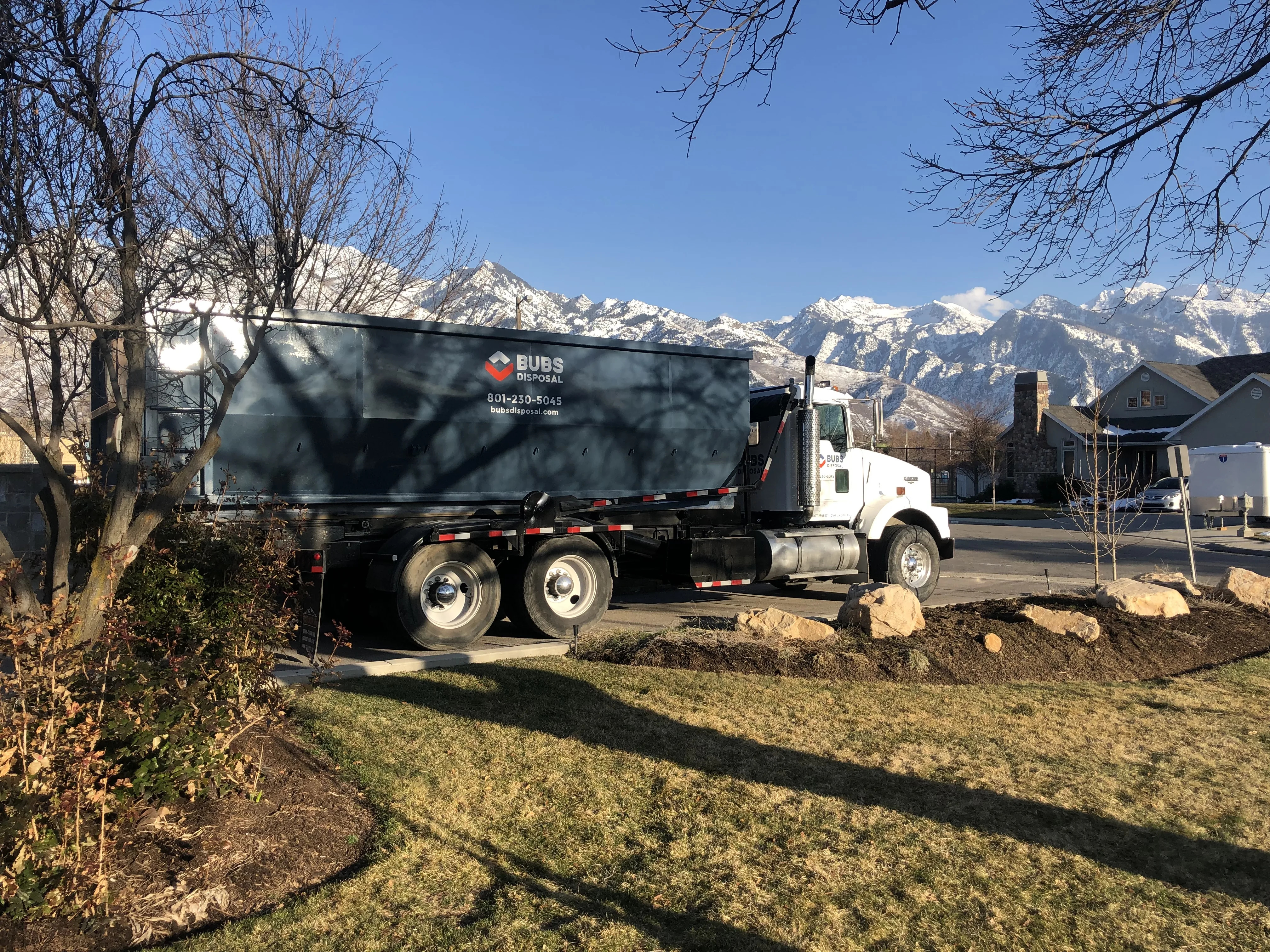 Bubs Disposal hook-lift truck delivering a residential dumpster in the snow