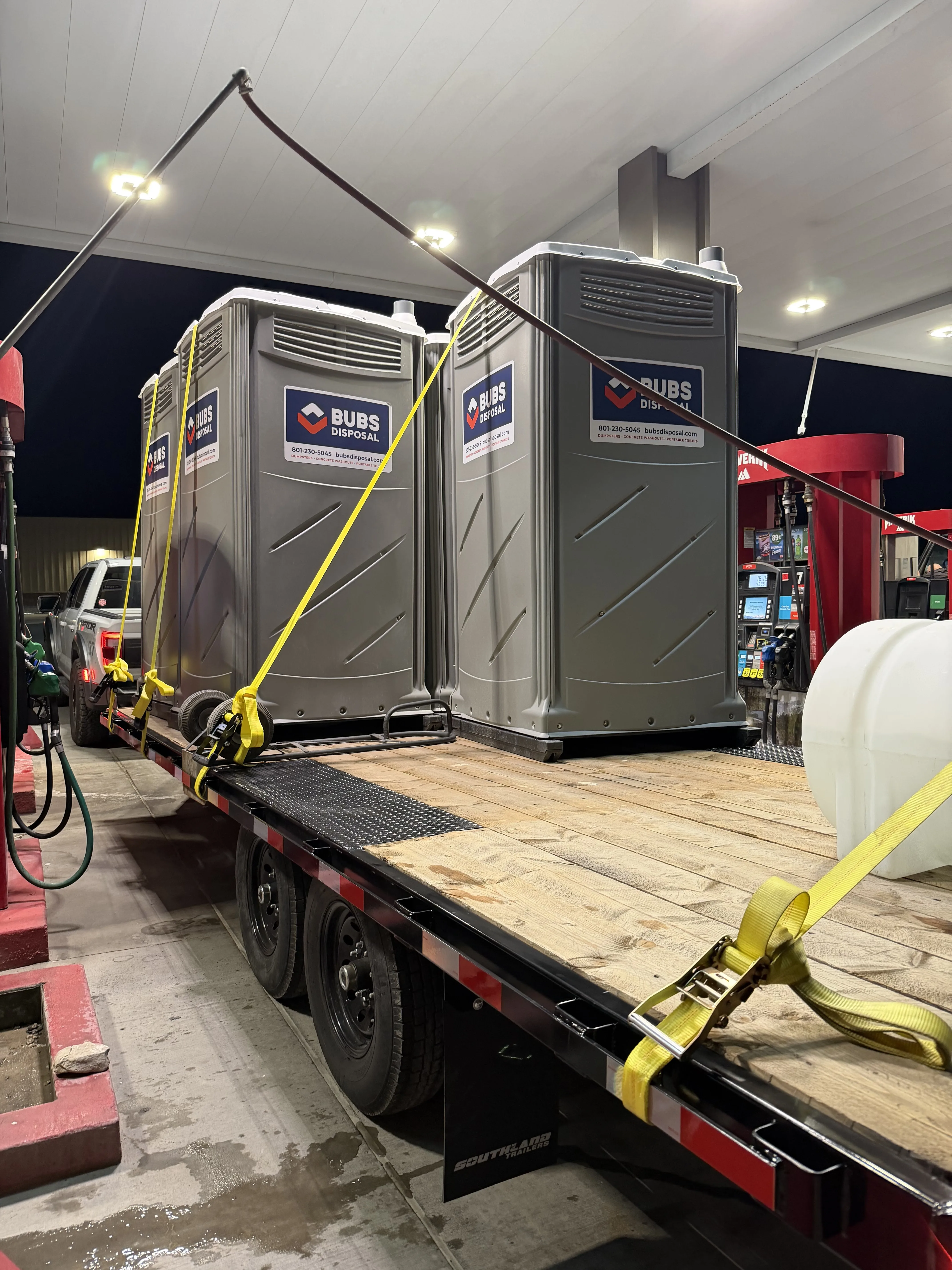 Two Bubs Disposal portable toilets strapped to a flatbed trailer for late-night delivery