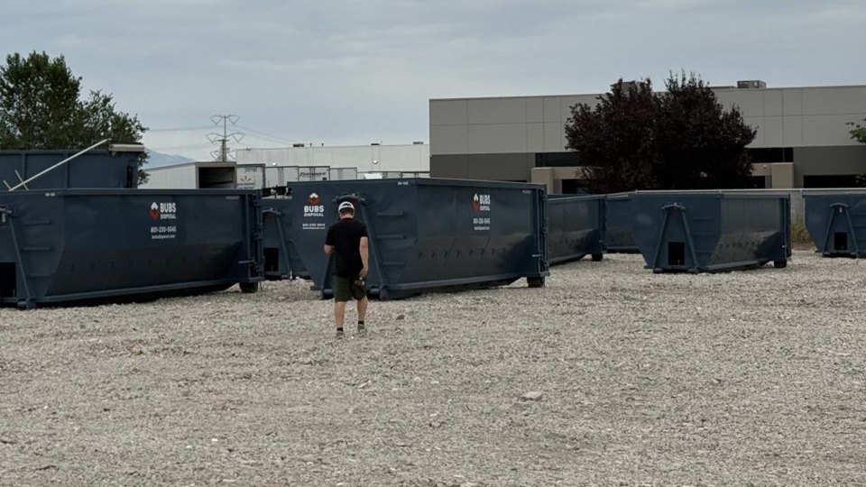 A person standing in the Bubs Disposal yard among a row of roll-off dumpsters
