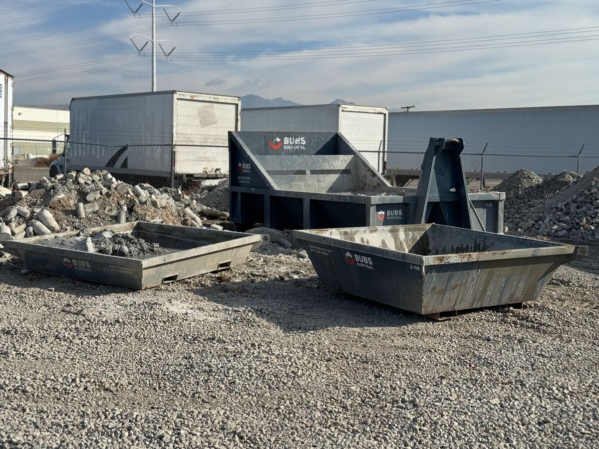 Two Bubs Disposal washout pans and a washout roll-off at the yard, with piles of broken concrete waiting to be crushed.